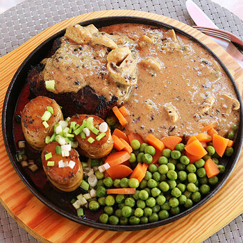 Pepper steak with fondant potatoes, mushrooms, carrots and peas.