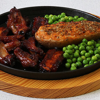 Honey glazed pork ribs with stuffed jacket potato and peas.