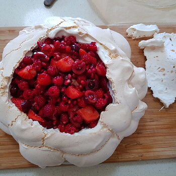 Pavlova being filled with red berries