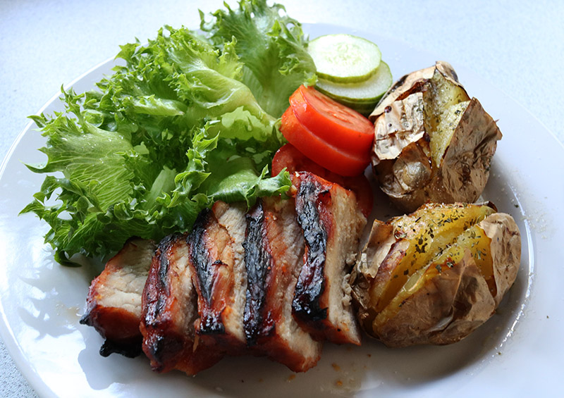 Char sui with grass and tomatoes and jacket potatoes.