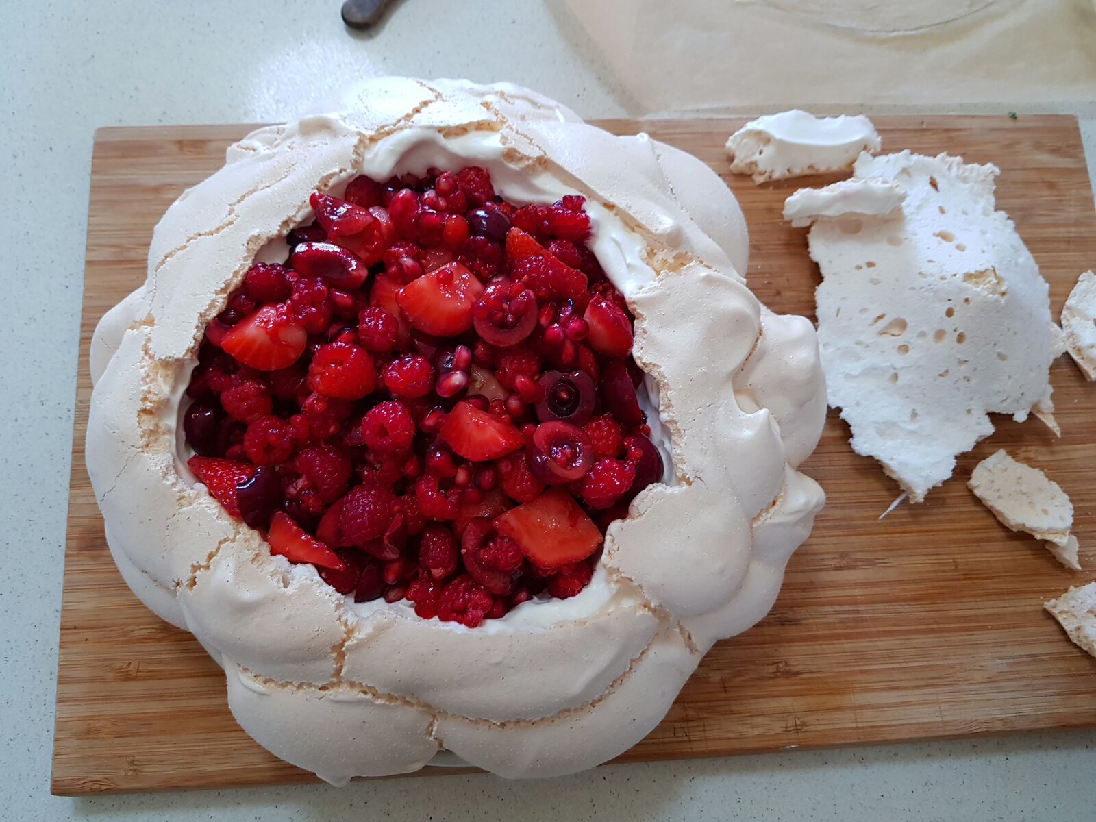 Pavlova being filled with red berries