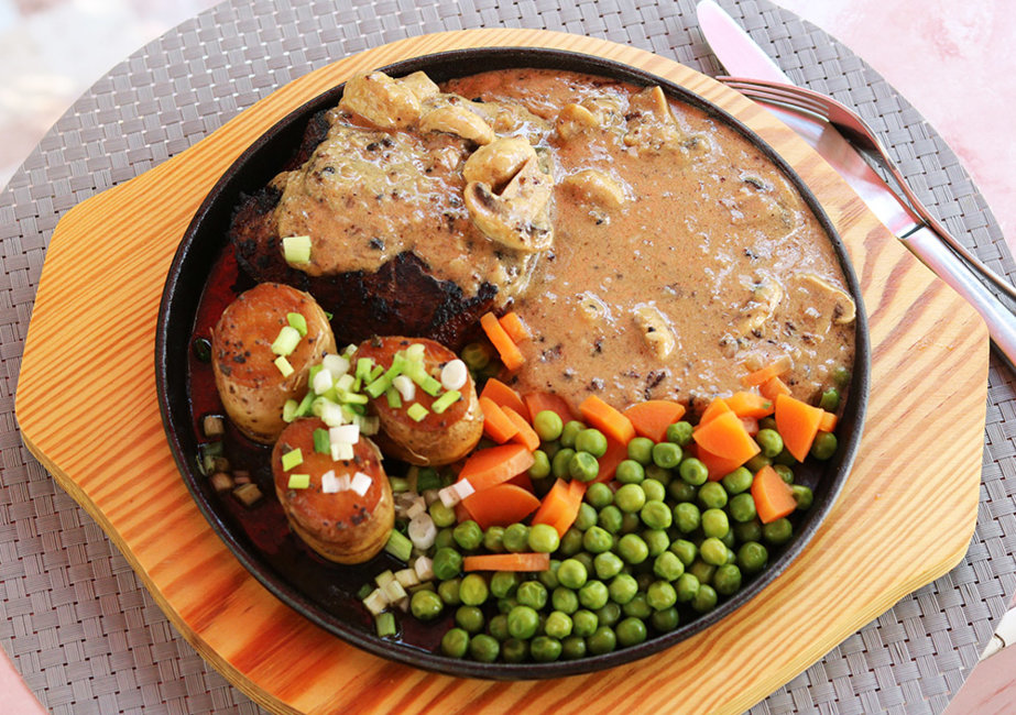 Pepper steak with fondant potatoes, mushrooms, carrots and peas.